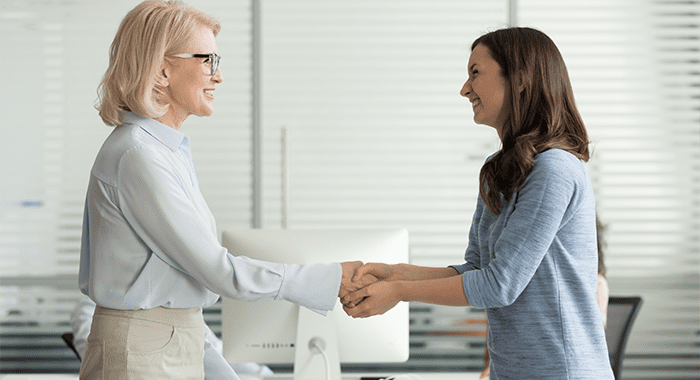 Happy young girl intern student worker get appreciated promoted hired rewarded handshaking helpful female old boss teacher, businesswomen handshake in office as gratitude recognition thanks concept