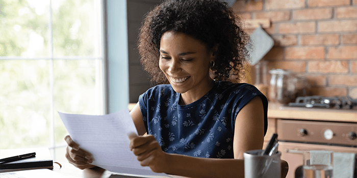 Joyful young mixed race female open paper written letter happy to read positive news from friend. Satisfied self employed black businesswoman get official answer about receiving credit loan from bank